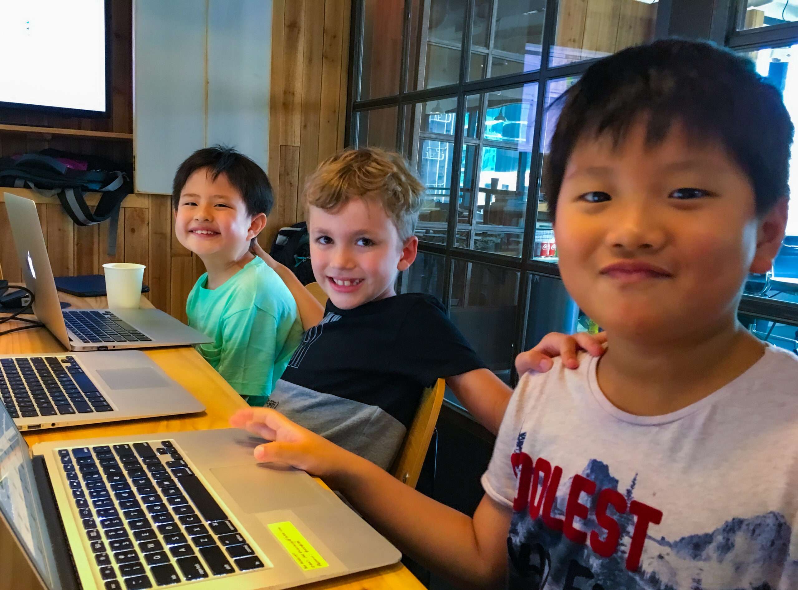 Three students having fun learning coding in a classroom at Tiny Code Hong Kong